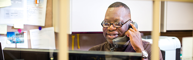 Man sitting in front of a computer, talking on the phone in an office